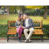 Outdoor cast iron patio bench with solid wood seat, comfortably seating three adults, perfect for garden relaxation.