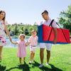 Giant carry storage bag in red and blue, designed for 4 in a Row game, being carried by a family near a lake.