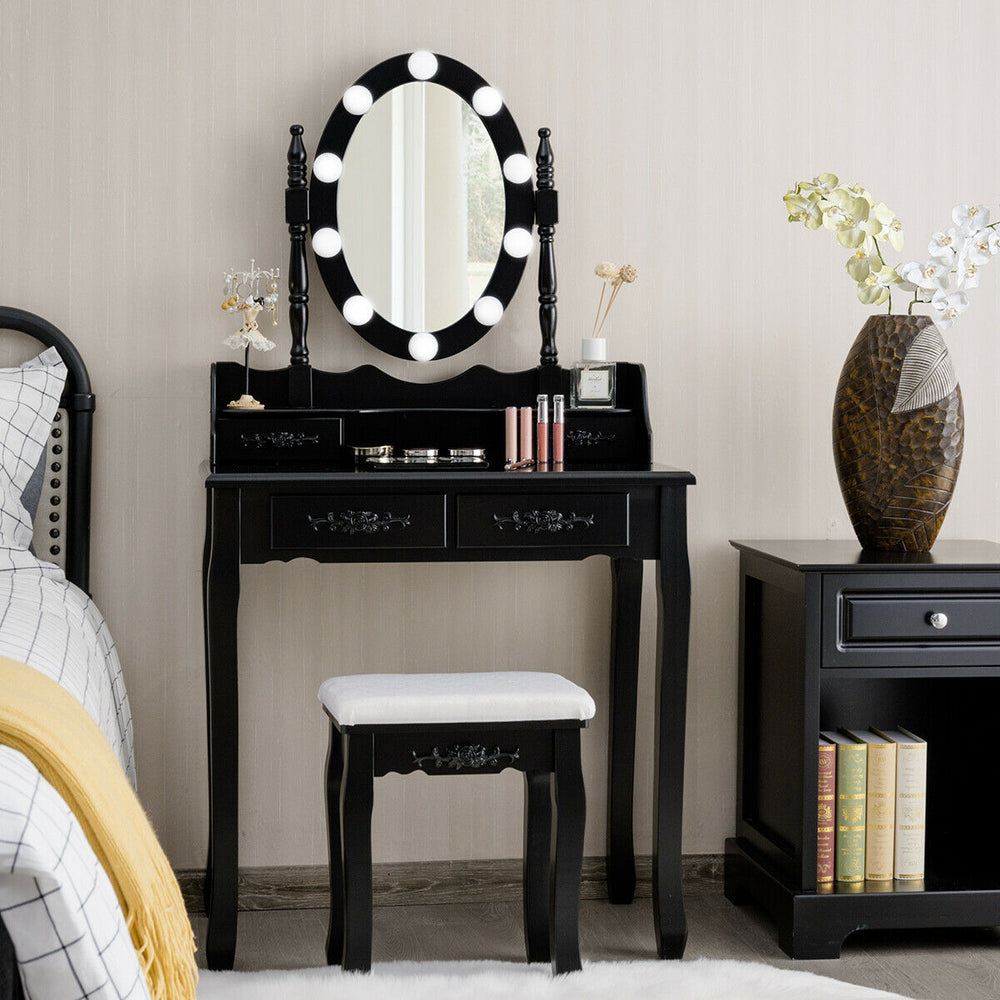 Black makeup dressing table with lighted mirror, cushioned stool, and four drawers for ample storage in elegant design.