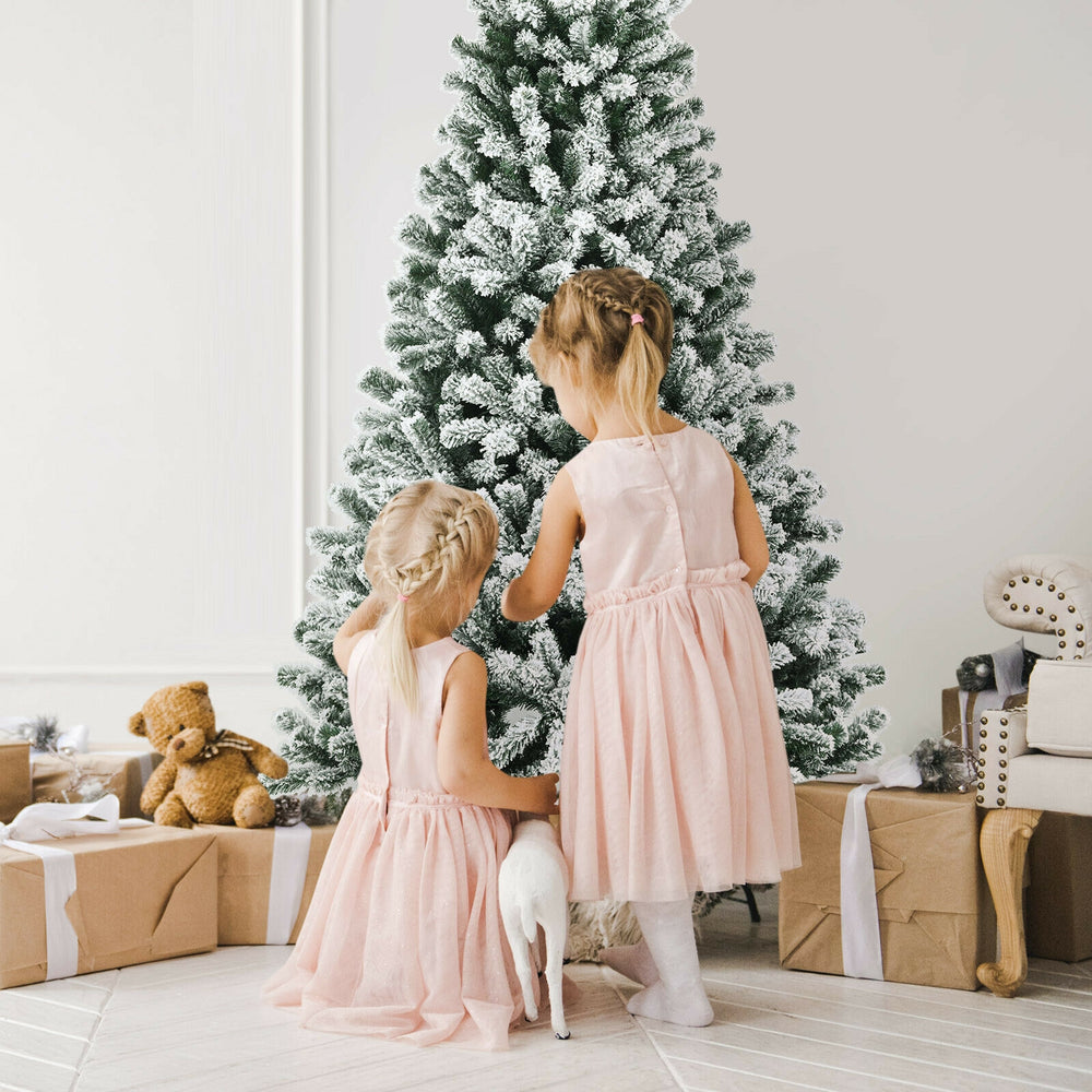 Two children decorating a 6-foot pre-lit snow flocked Christmas tree with 928 tips for a festive atmosphere.