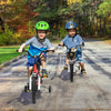Two children riding the 12-inch red kids bike with training wheels, designed for ages 3-4, on a scenic path.