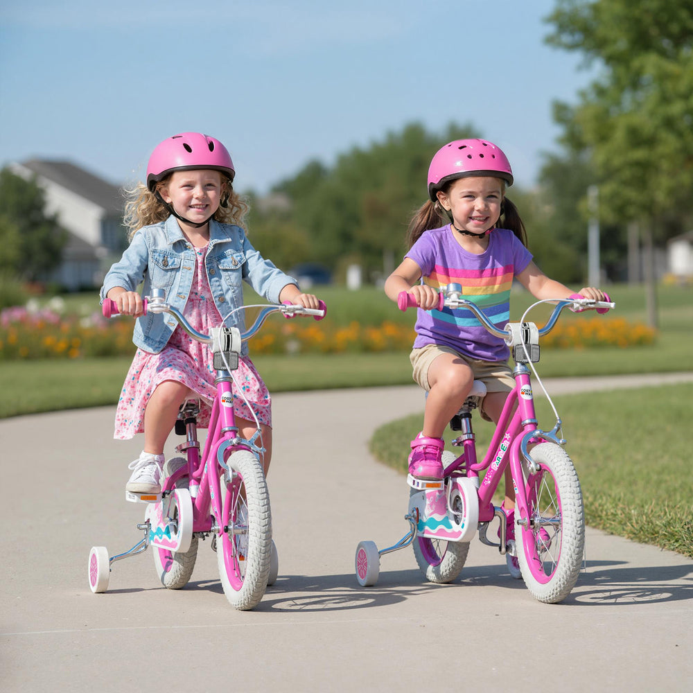 Two girls riding the pink 12-inch kids bike with adjustable handlebars and training wheels in a park setting.