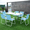 Six blue folding beach chairs with a solid steel frame arranged around a table on a lawn, perfect for outdoor.