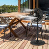 16-inch black oscillating pedestal misting fan with adjustable height, placed on a patio for outdoor cooling.