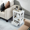 White 2-tier nightstand with storage drawer, open shelf, and X-shaped structure for versatile use beside a sofa.
