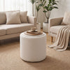 Round beige storage ottoman with a reversible lid, flat wood top, and soft Sherpa fabric for versatile use in any room.