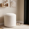 Round beige storage ottoman with a reversible lid, soft Sherpa fabric, and flat top for versatile use in any room.