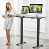 Electric height adjustable standing desk in black with a user reading, showcasing ergonomic benefits for workspace.