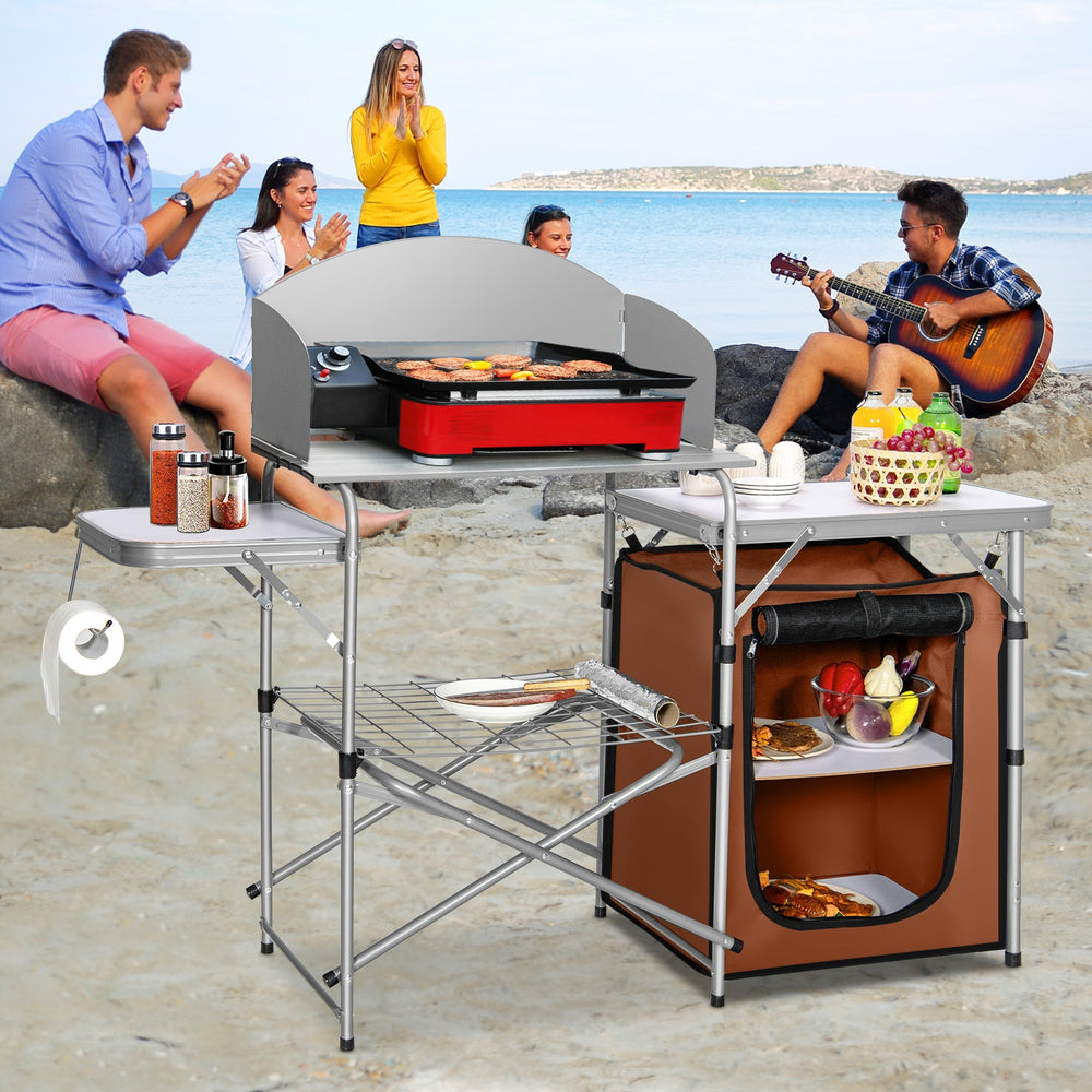 Foldable outdoor BBQ grilling table with windscreen, featuring aluminum construction, side tables, and storage bag for.