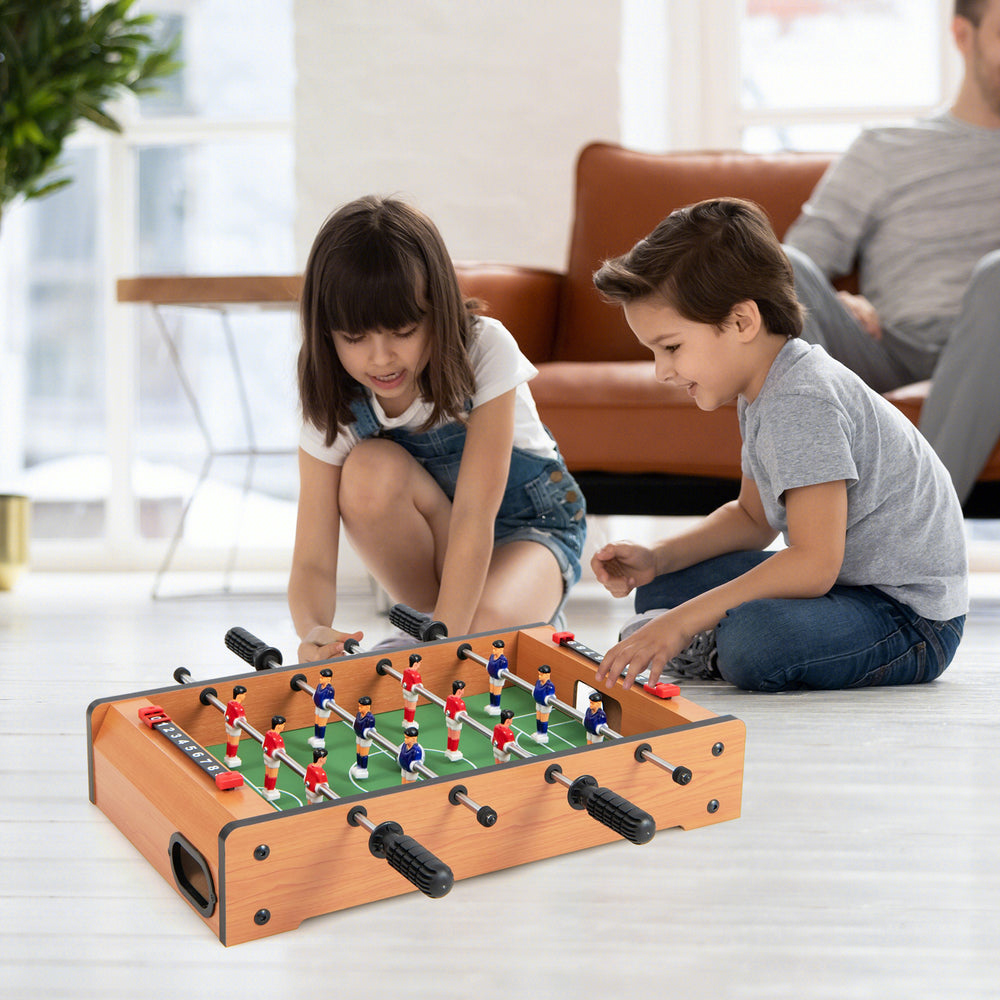 Children playing with a 20-inch indoor competition soccer table featuring strong wood construction and solid steel rods.