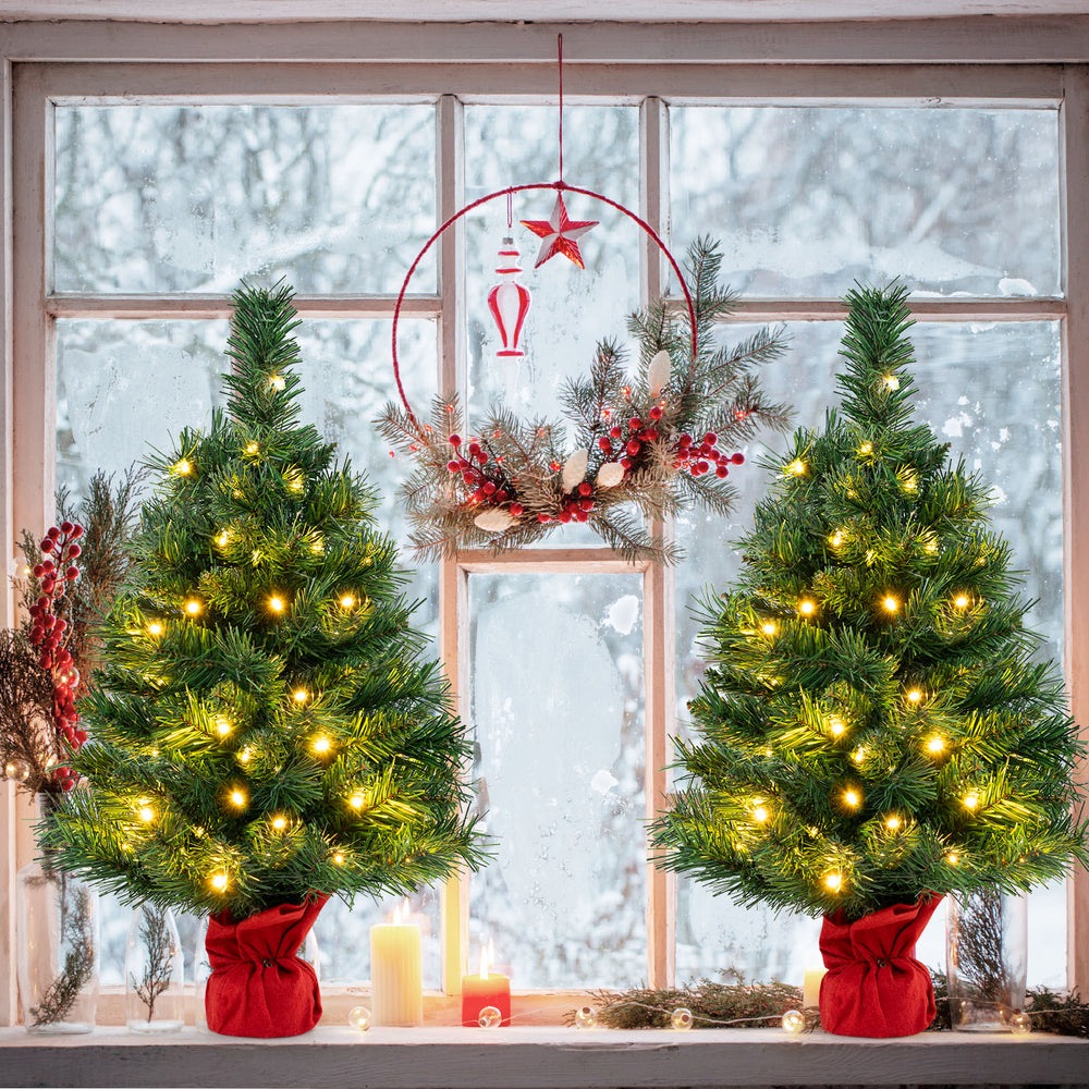 Mini pre-lit 24-inch Christmas tree with warm white LED lights, red cloth base, perfect for festive tabletop decoration.