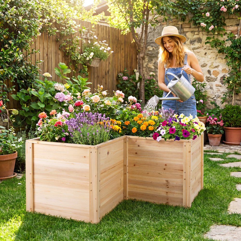L-shaped wooden raised garden bed made of natural fir, featuring vibrant flowers and a gardener watering plants.