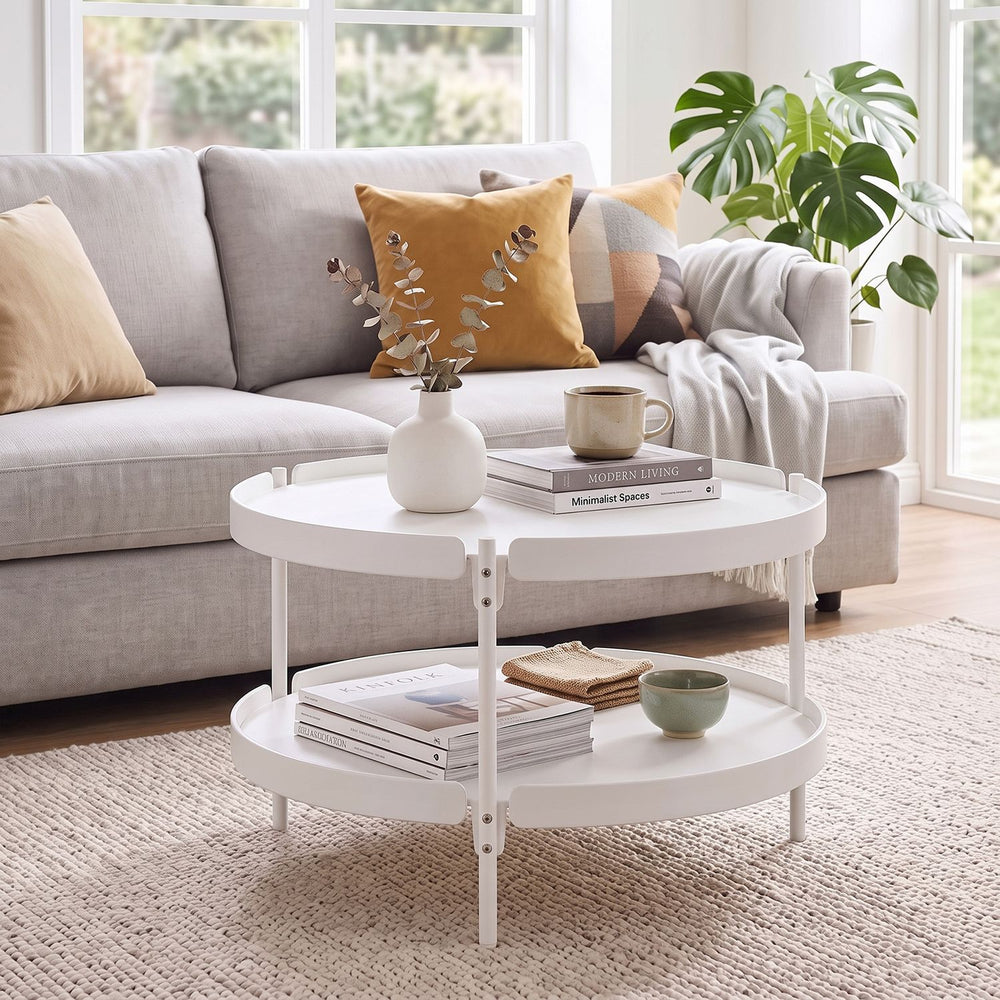 Round white coffee table with plastic top and metal legs, featuring an open shelf for extra storage in small spaces.