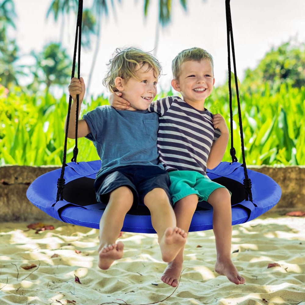 Two children happily swinging on a 40-inch blue flying saucer tree swing, perfect for outdoor play and relaxation.