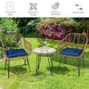 Two navy cushioned rattan chairs and a glass-top table in a garden, perfect for outdoor patio relaxation.