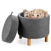 Round gray fabric storage ottoman with removable lid, wooden tray, and soft padded seat for versatile use in any room.