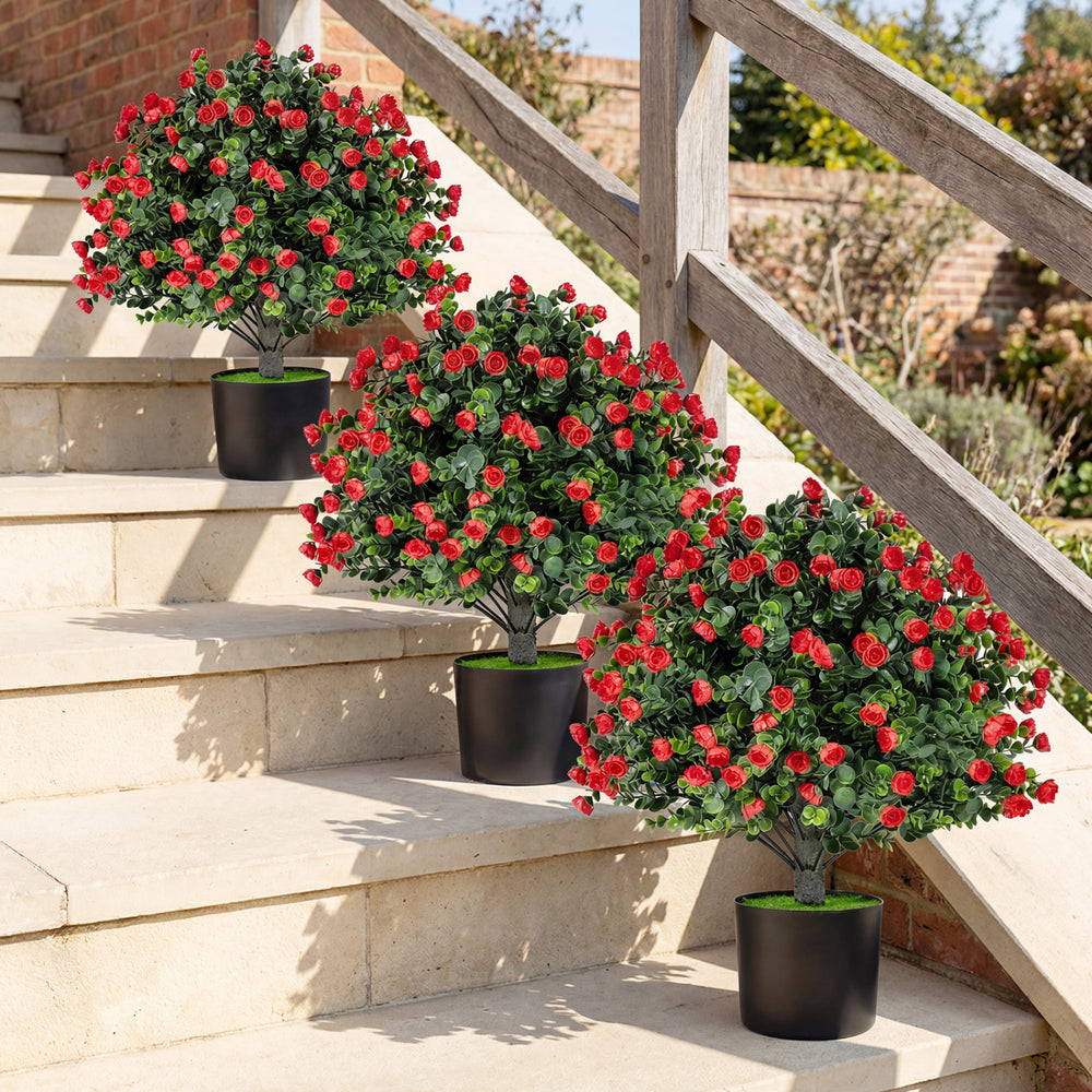 Artificial rose topiary ball trees in black cement-filled pots, featuring vibrant red roses and green leaves for.