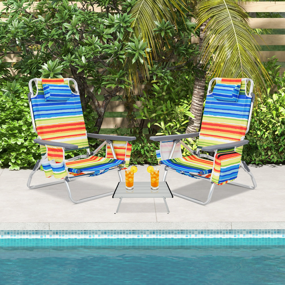 Two colorful folding beach chairs with a side table, perfect for outdoor relaxation by the pool.