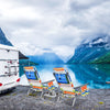 Two colorful folding beach chairs with a side table by a lake, perfect for outdoor relaxation and leisure activities.