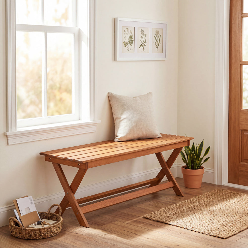 2-seat wooden garden patio bench with X-shaped legs, placed indoors with a cushion and decorative plants.