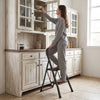 Two-step folding ladder with handrail and wide anti-slip pedals, ideal for reaching cabinets and everyday tasks.