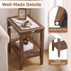 Walnut 2-tier narrow side table with marble-inspired tempered glass top and open storage shelf, shown beside a bed.