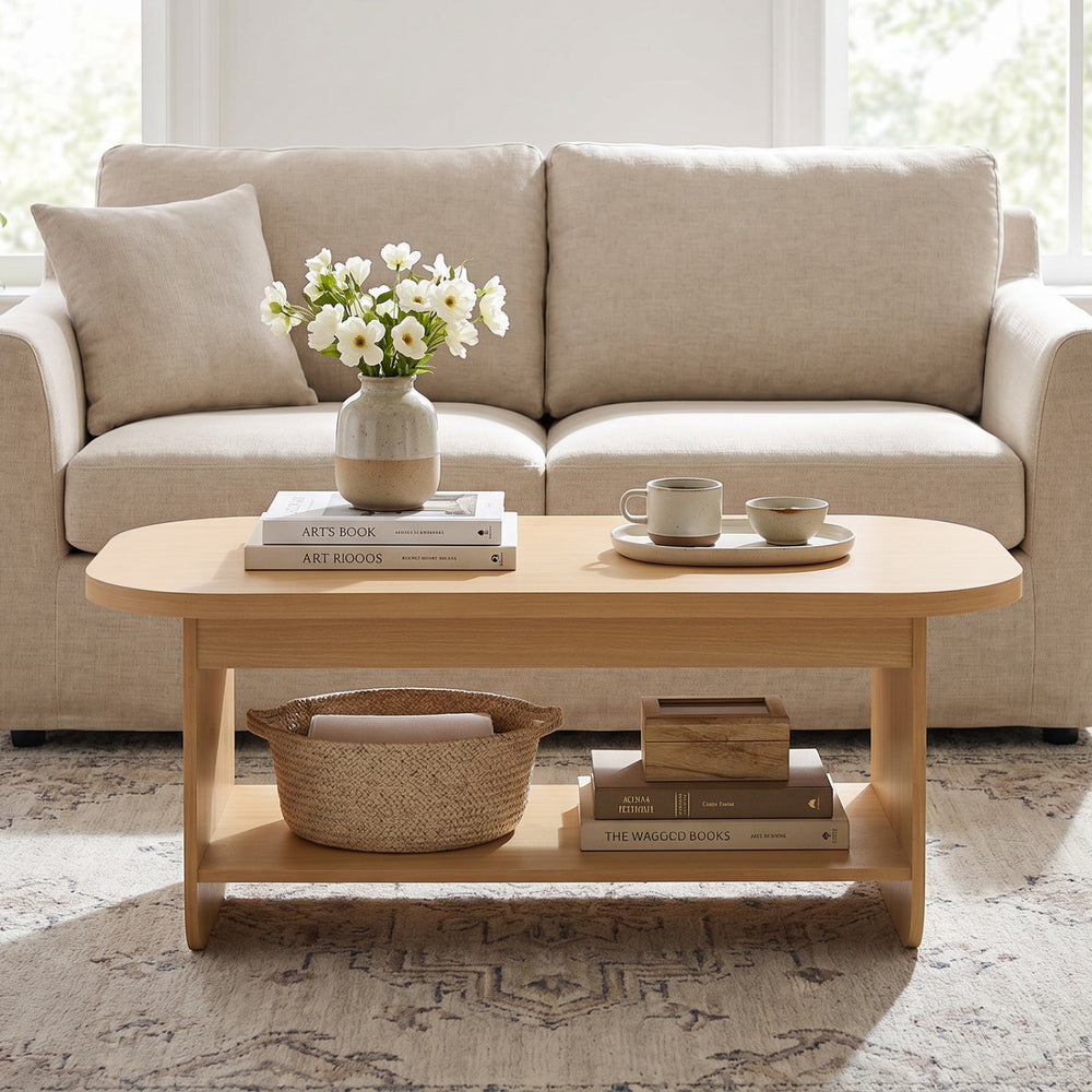 Oval coffee table with bottom storage shelf in natural wood, featuring a minimalist design for living room use.