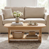 Oval coffee table with bottom storage shelf in natural wood, featuring a minimalist design for living room use.