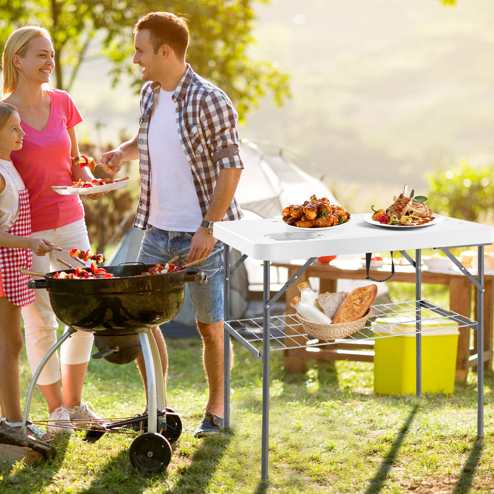 Folding fish cleaning table in white with double sinks, ideal for camping and picnics, shown in outdoor setting.
