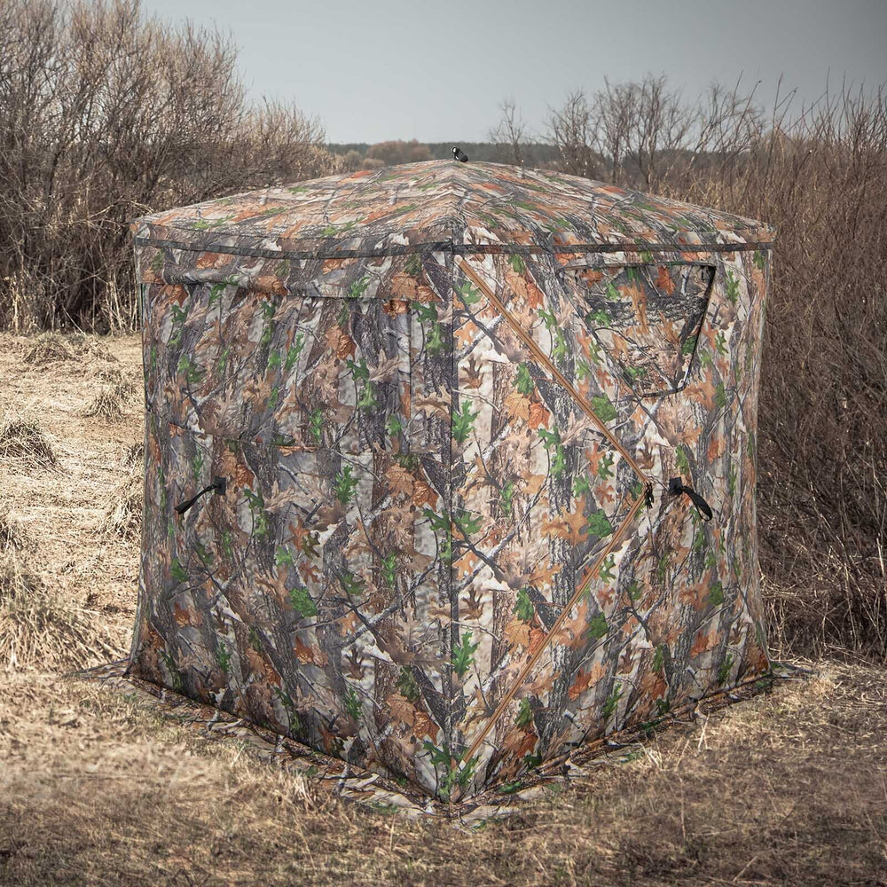 Portable 2-3 person hunting blind in camouflage, featuring multiple windows and a durable pop-up design for easy setup.