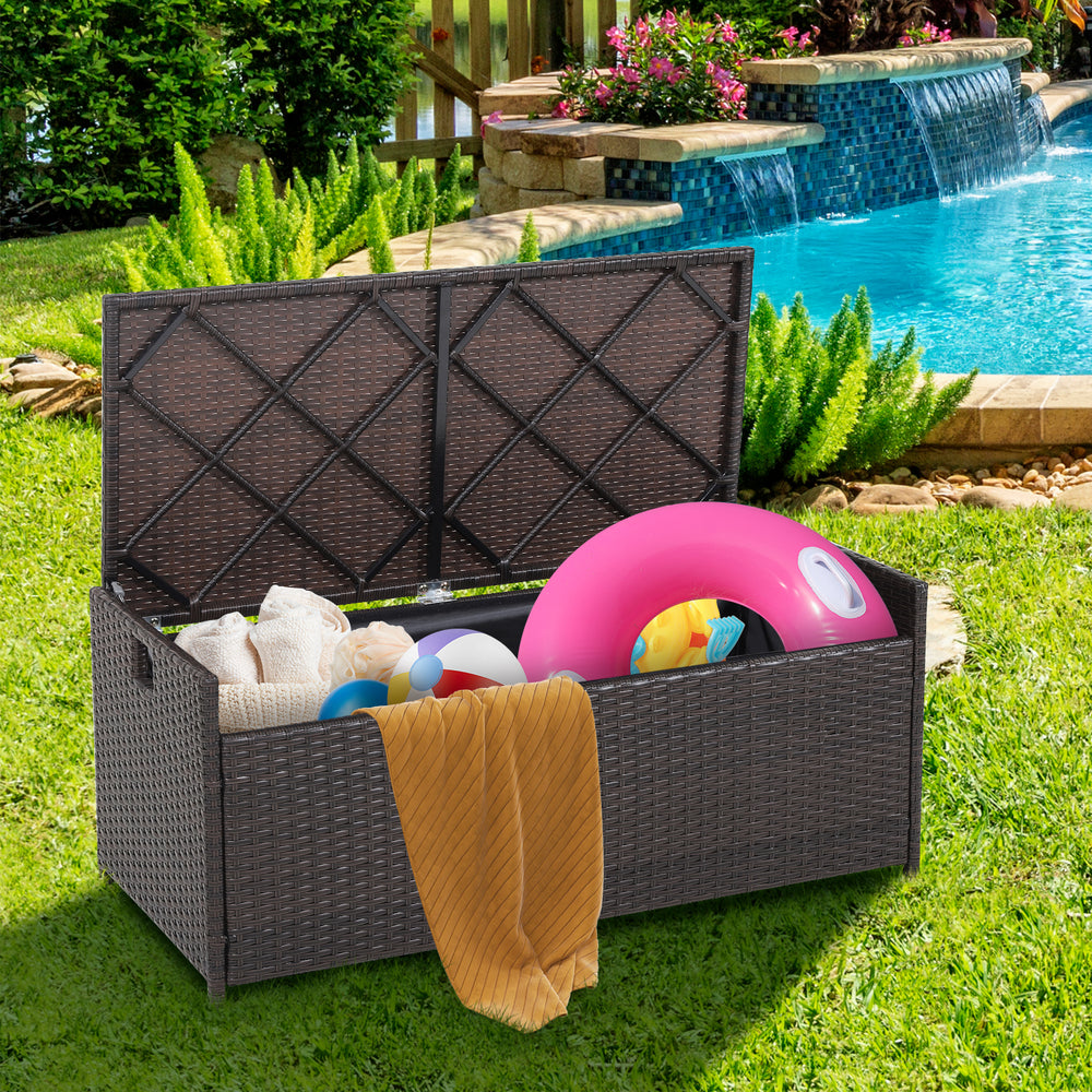Patio storage bench with seat cushion, made of brown PE rattan, ideal for outdoor storage and seating by the pool.
