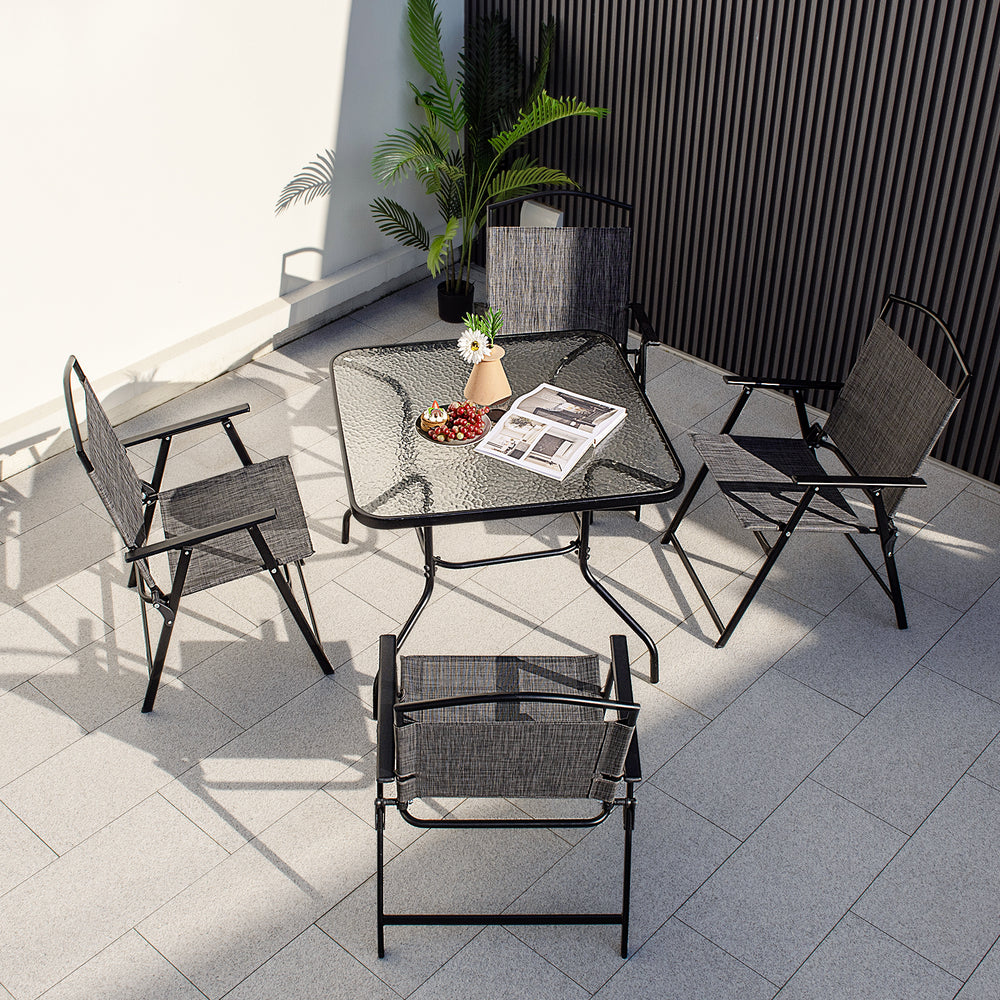 Four stylish folding chairs arranged around a 34-inch outdoor dining table with a tempered glass top and umbrella hole.