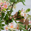 Hand adjusting the lifelike leaves of a 36" artificial impatiens tree with pink silk flowers and mini fruits for decoration.