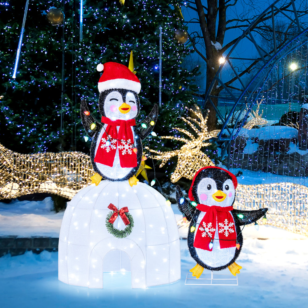 3D pre-lit igloo with cute penguins in scarves, adorned with 170 cold-white LED lights for festive indoor or outdoor.