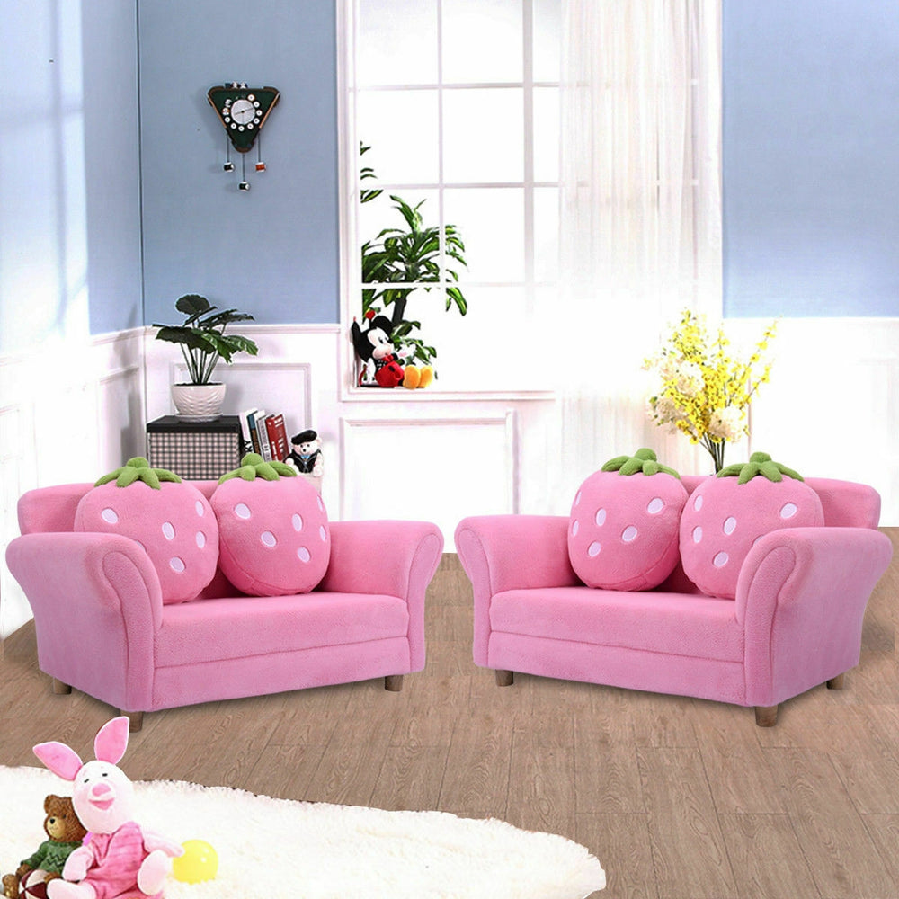 Kids strawberry armrest sofa in pink with two matching strawberry pillows, perfect for children's leisure and.