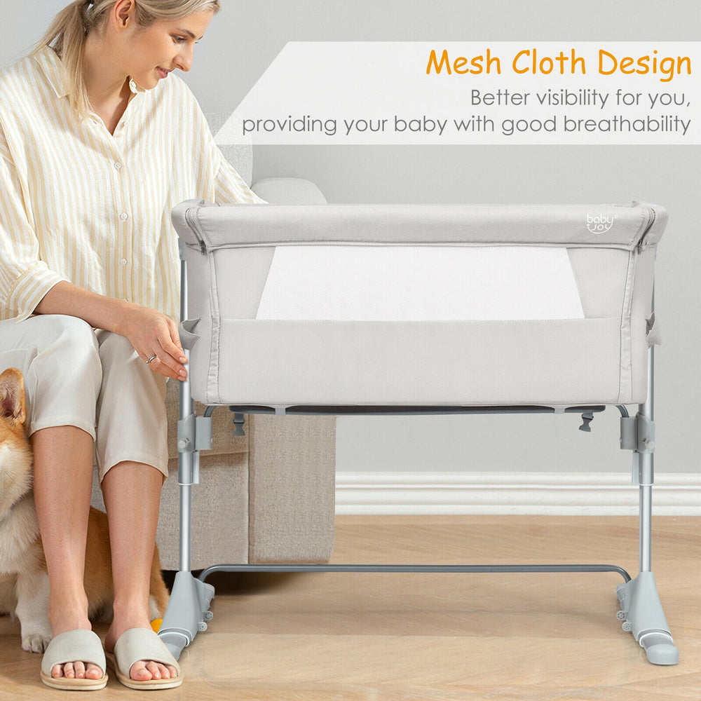 Portable beige bedside crib with mesh sides, adjustable height, and detachable mattress for safe baby sleep.