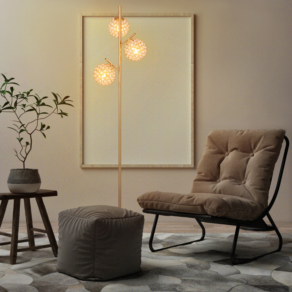 Three-globe floor lamp with golden finish, featuring acrylic shades and foot switch, perfect for home or cafe lighting.