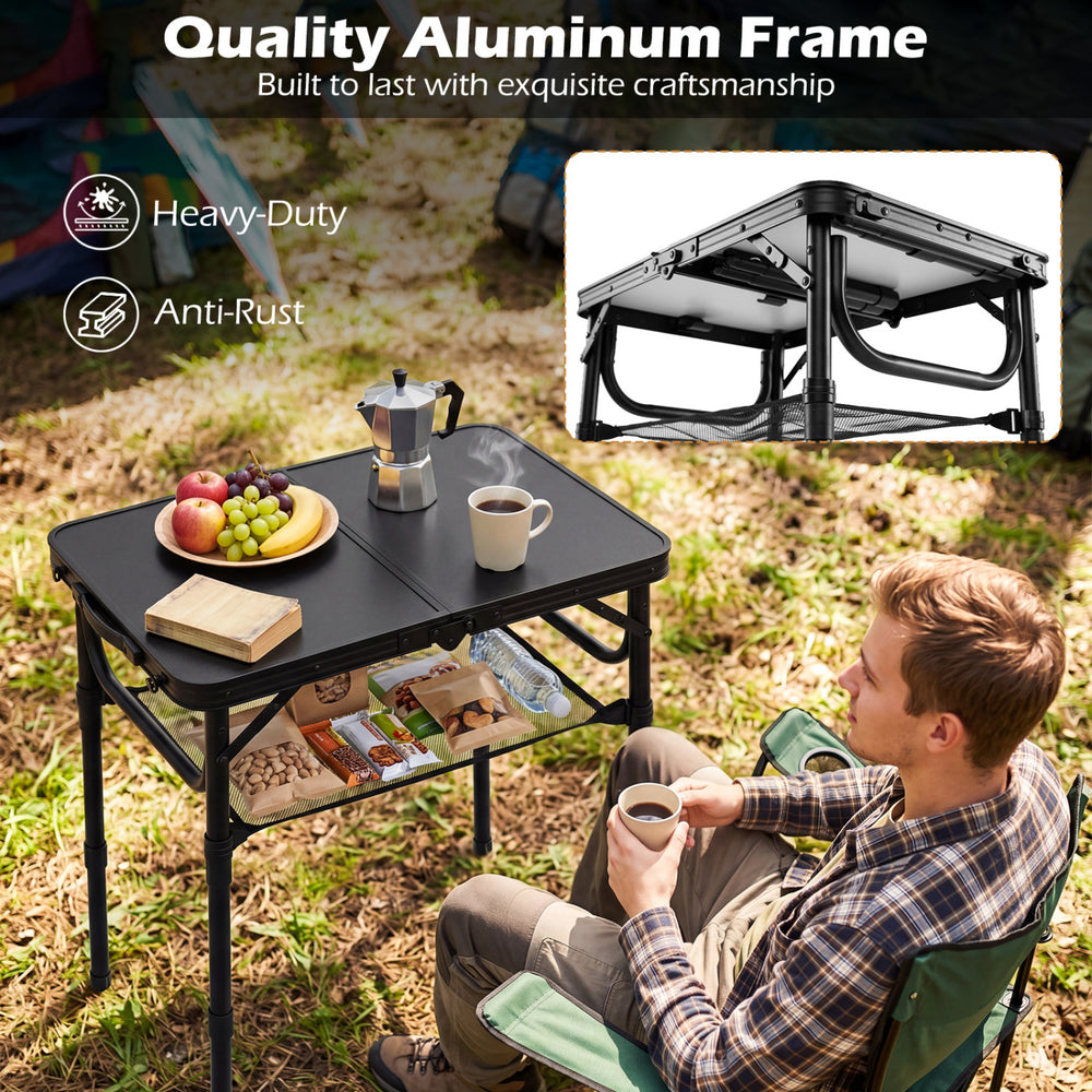 Folding camping table in black with aluminum frame, featuring a large storage net and handle, ideal for outdoor use.