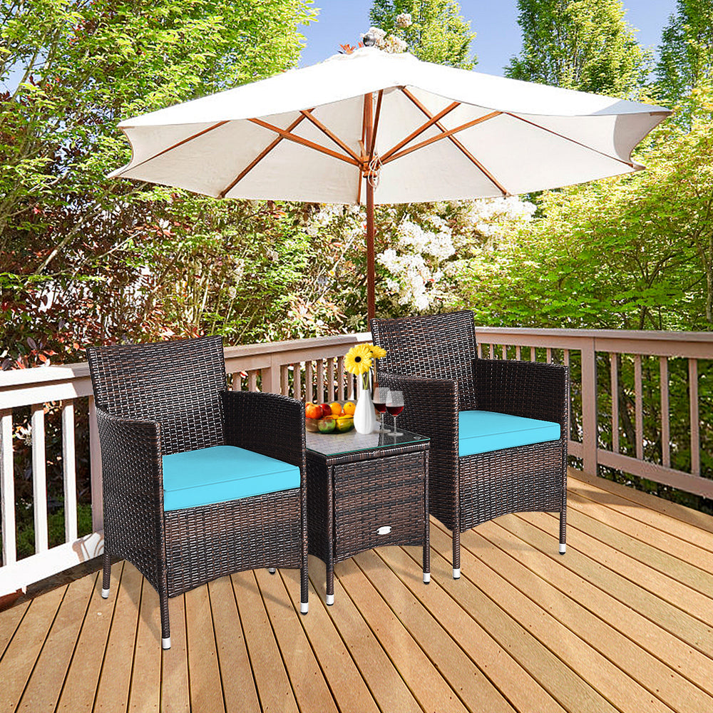 Two blue-cushioned rattan chairs and a glass-top table in a patio setting, perfect for outdoor relaxation.