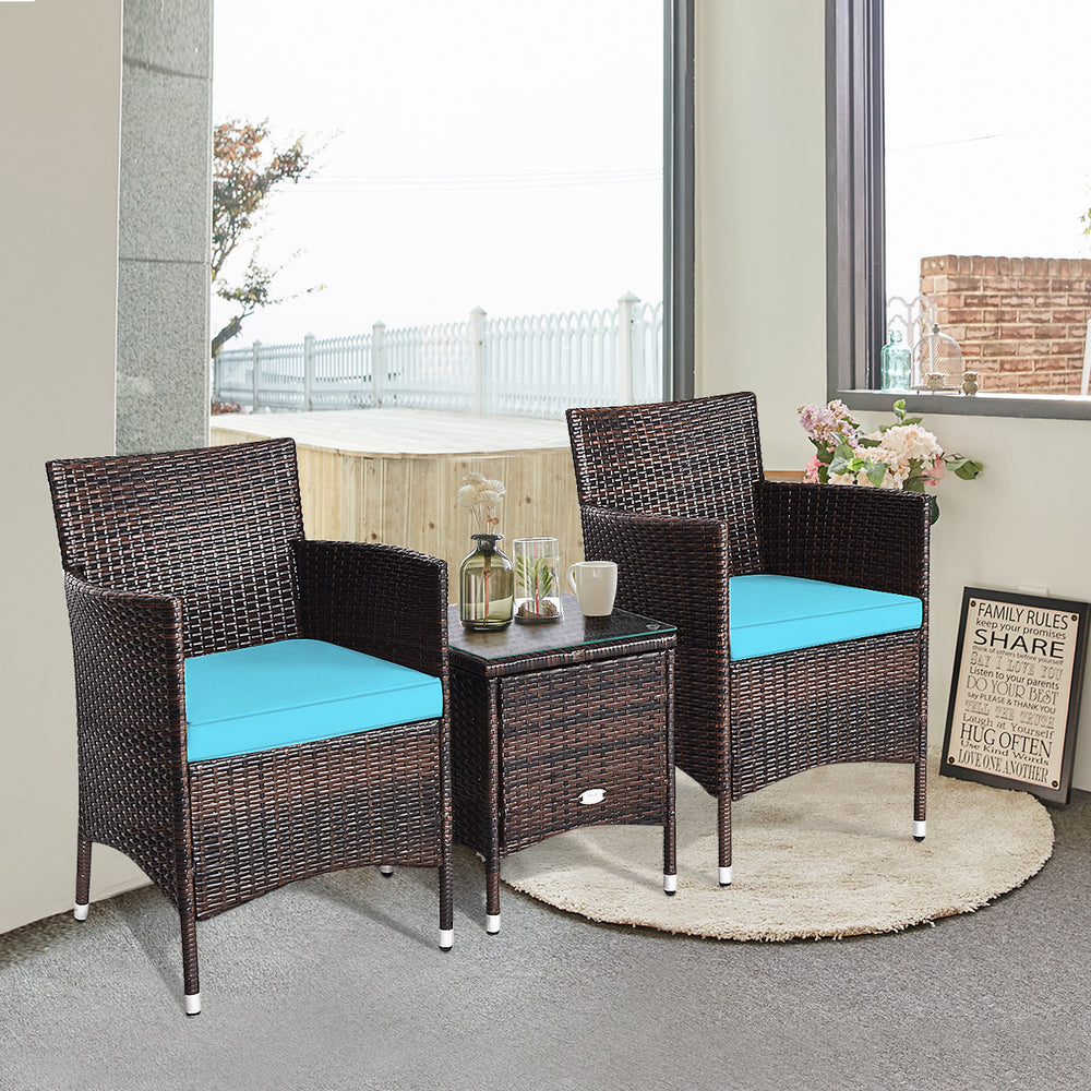 Two blue-cushioned rattan chairs and a glass-top coffee table in a cozy indoor setting, ideal for outdoor relaxation.