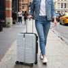 Lightweight gray hardside luggage set with 8-spinner wheels, shown being wheeled on a city street for easy travel.
