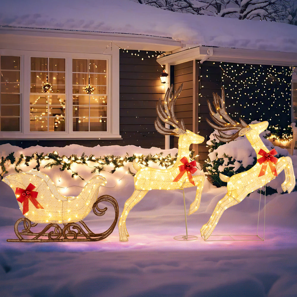 Lighted reindeer and sleigh set with 280 warm white LEDs, red bows, perfect for outdoor Christmas decoration.