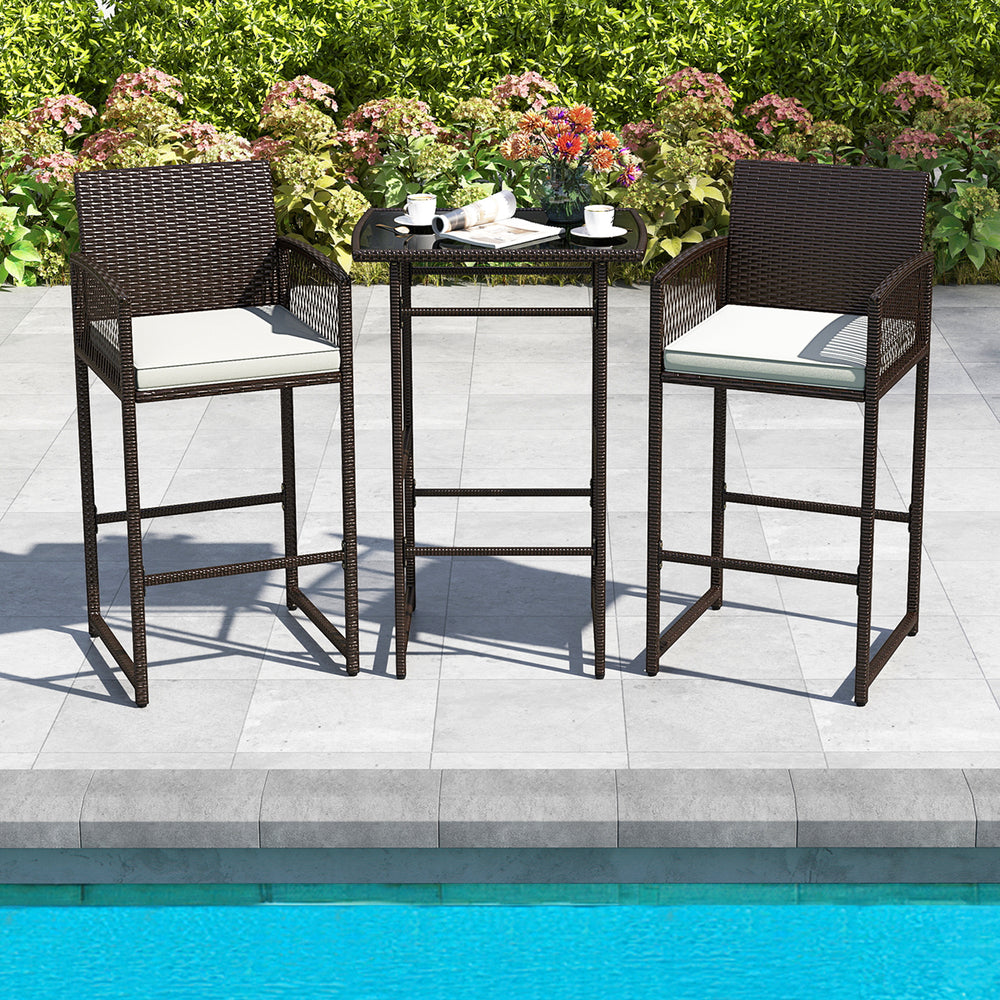 Bar height table and two armchairs with white cushions, made of PE wicker, perfect for poolside relaxation.