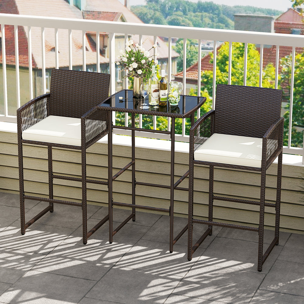 Bar height table and two wicker chairs with white cushions, perfect for outdoor patio or garden relaxation.
