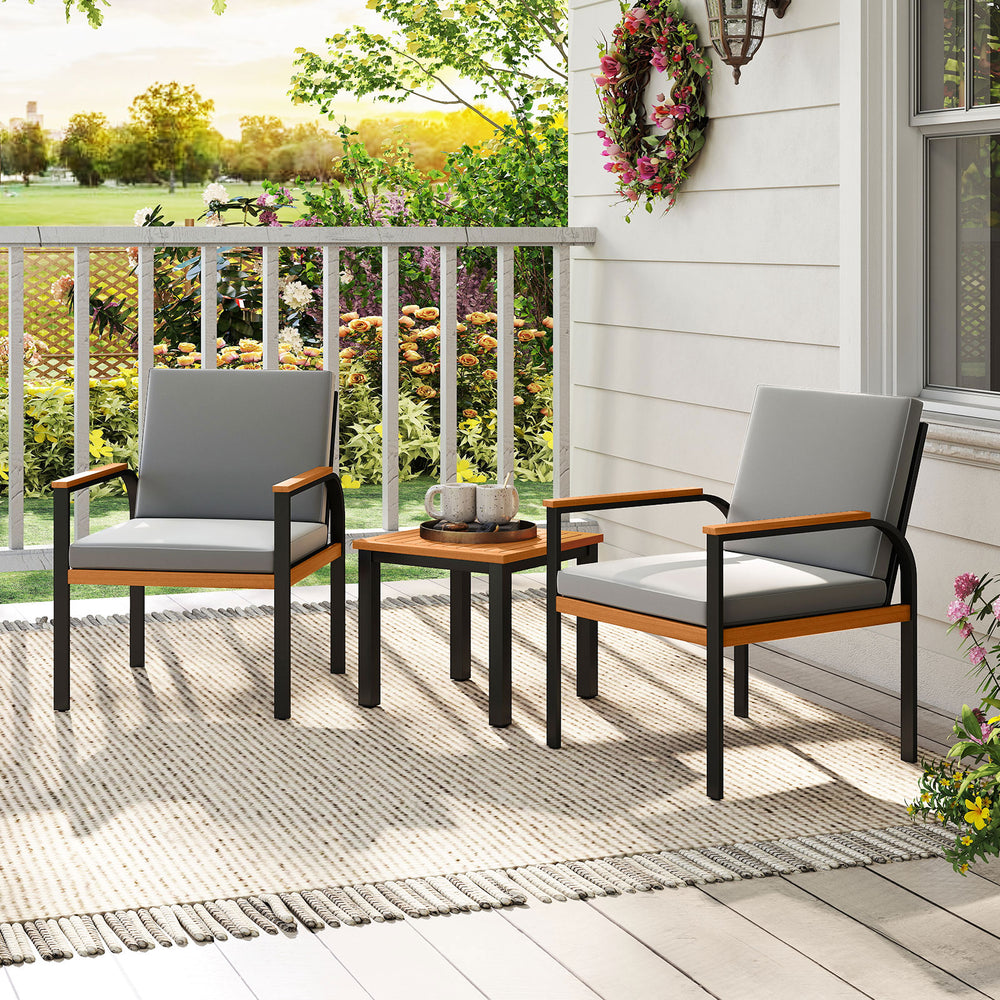 Two grey cushioned chairs with acacia wood armrests and a coffee table on a patio, perfect for outdoor conversation.