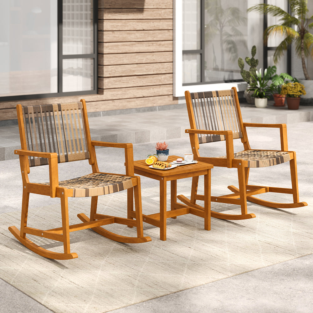 Two acacia wood rocking chairs with rattan seats and a compact side table, perfect for backyard relaxation.