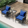 Cushioned patio chairs with navy blue cushions and tempered glass coffee table on a wooden deck by the pool.
