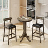 Round wood bar table set with pedestal base and two armless stools, featuring padded seats for comfort and farmhouse.