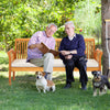 Patio 3-seat wood bench with soft white cushions, accommodating three people for garden relaxation.