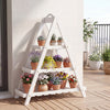 3-tier white plant stand made of solid fir wood, displaying potted plants on a balcony for indoor and outdoor use.